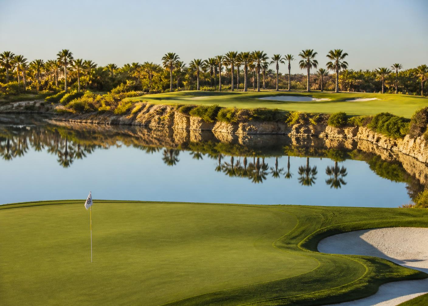 Golf green beside the quarry lake with palm trees